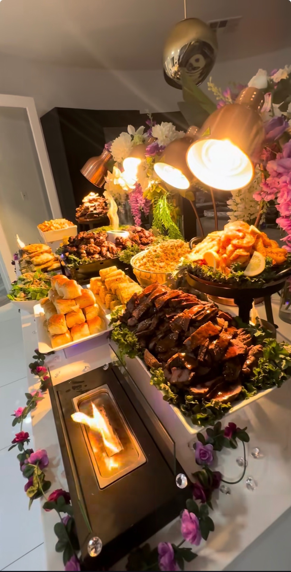 Indoor catering buffet with heat lamps, carving station, florals and flame