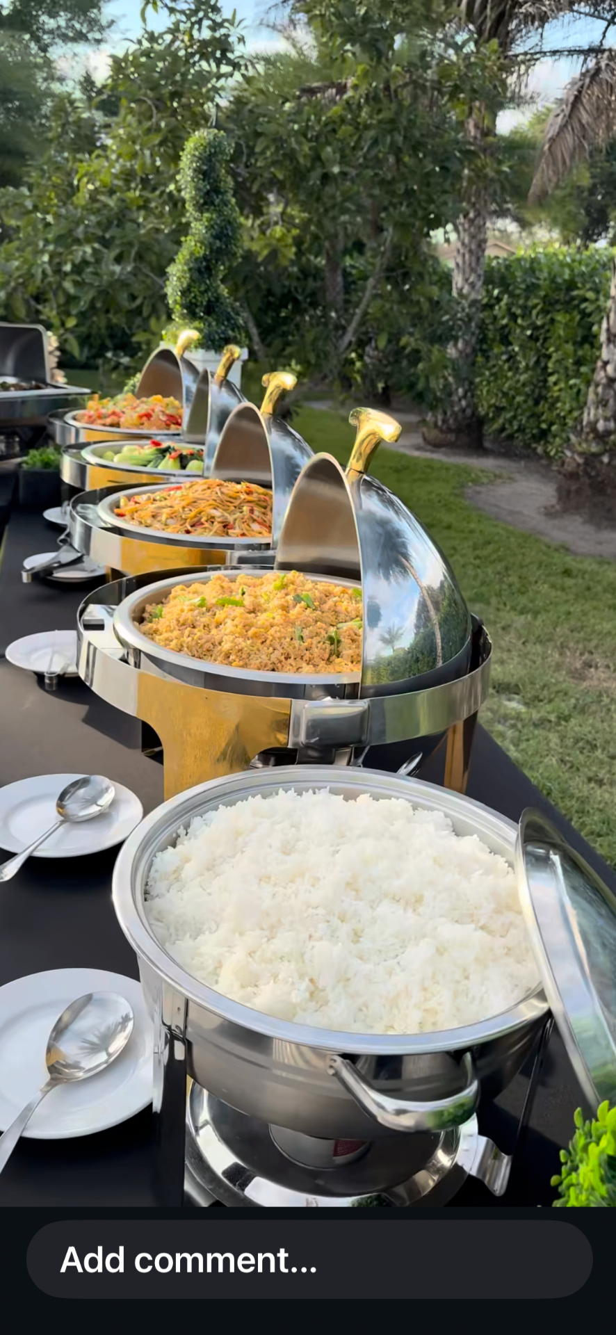 Gold and silver chafing dishes lined up at an outdoor catered event